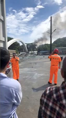 People stand a distance away from the collapsed Nanfang'ao Bridge after a typhoon hit Su'ao in Yilan county