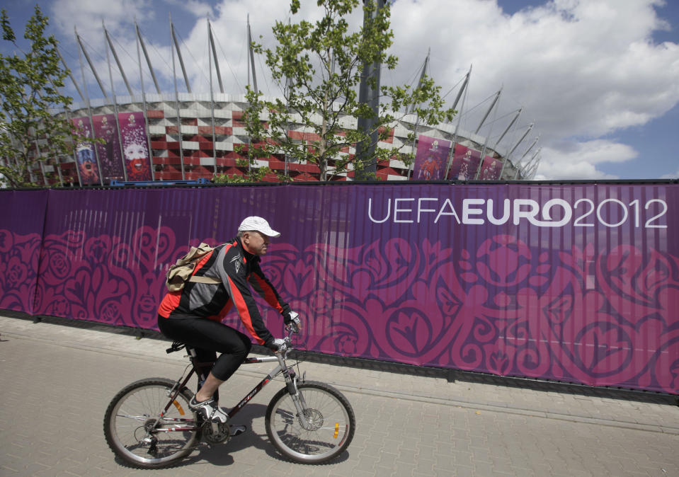 A cyclist passes the decorated fence surrounding Poland’s National Stadium in Warsaw, Poland, on Wednesday May 30, 2012. Poland is in full preparation mode as it counts down to the Euro 2012 football tournament that it is co-hosting with Ukraine starting on June 8. (AP Photo/Czarek Sokolowski)