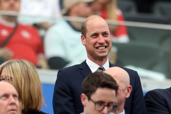 Prince William smiling while standing among a crowd of spectators