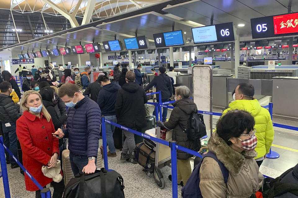 FILE - In this Jan. 30, 2020, file photo, travelers wearing face masks stand in line at the check-in counters for Cathay Pacific at Shanghai Pudong International Airport in Shanghai, China. The outbreak of the new virus threatens to erase $29 billion of this year's revenue for global airlines, mostly for Chinese carriers, as travel crashes worldwide, according to the International Air Transport Association. (AP Photo/Erika Kinetz, File)