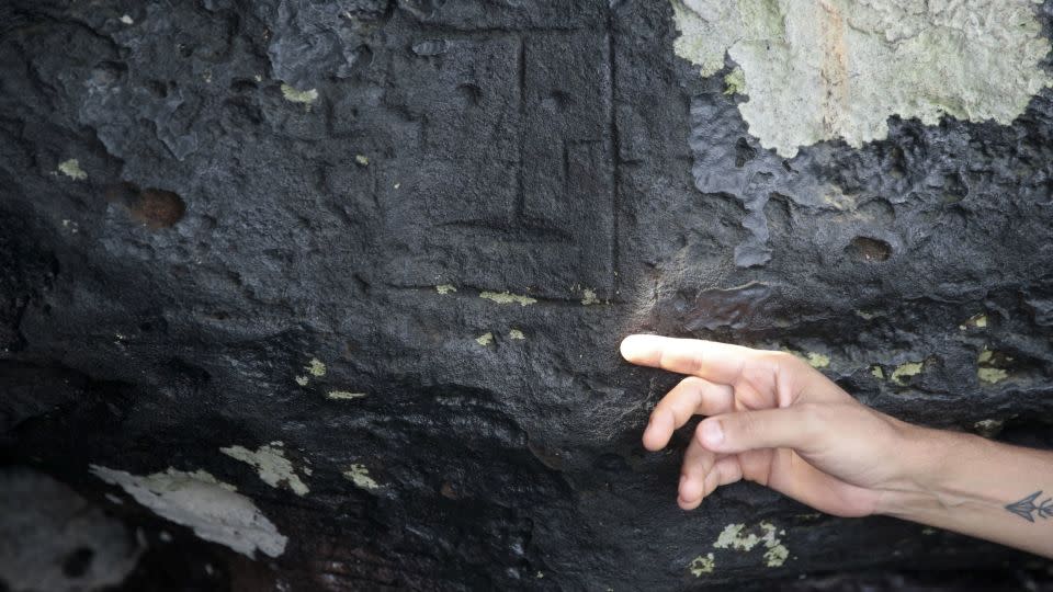 Institute for Public Health and Medicine (IPHAM) archaeologist Jaime de Santana Oliveira points to one ancient stone carving. - Suamy Beydoun/Reuters