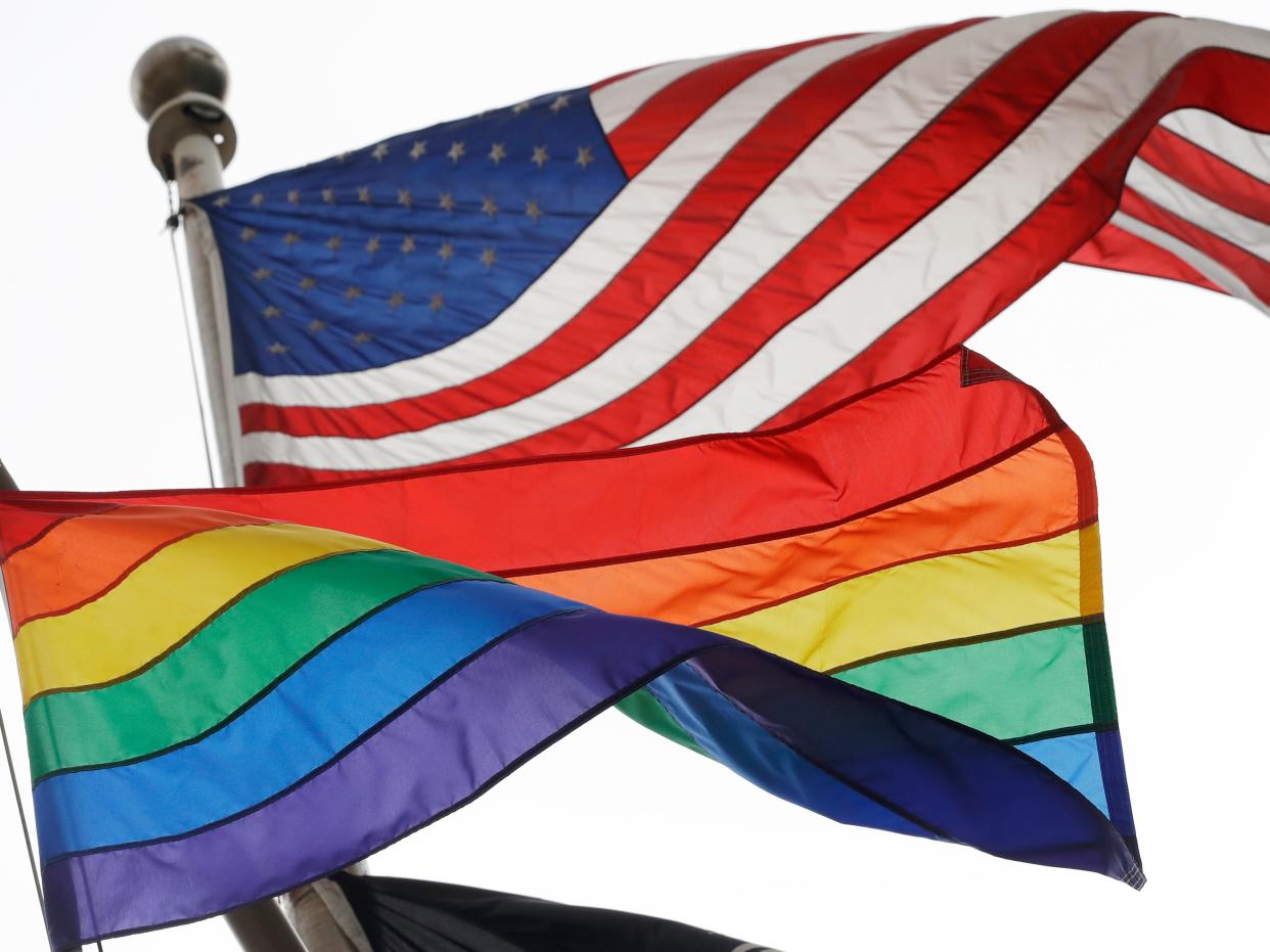 The Rainbow Flag, a symbol of LGTQ liberation, flies beneath the American flag.