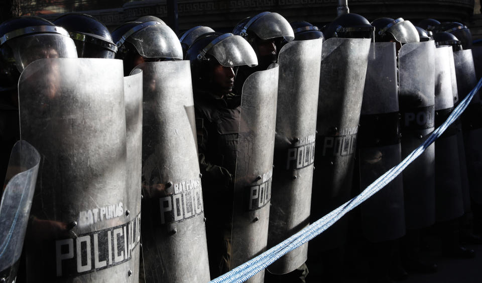 Police stand guard outside the top electoral court where protesters who are against the reelection of President Evo Morales wait for the final results of last weekend's presidential election in La Paz, Bolivia, Wednesday, Oct. 23, 2019. Morales said Wednesday his opponents are trying to stage a coup against him as protests grow over a disputed election he claims he won outright, while a nearly finished vote count had him teetering on the threshold between getting the win or having to go to a runoff. (AP Photo/Juan Karita)