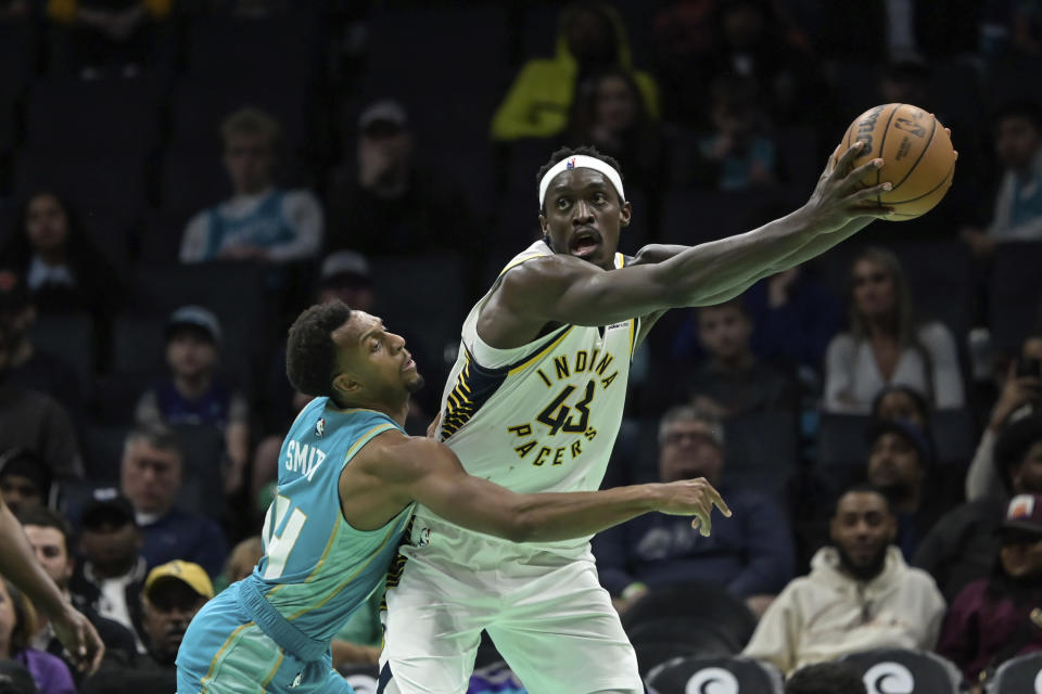 Charlotte Hornets guard Ish Smith, left, attempts to steal the ball from Indiana Pacers forward Pascal Siakam (43) during the second half of an NBA basketball game, Sunday, Feb. 4, 2024, in Charlotte, N.C. (AP Photo/Matt Kelley)