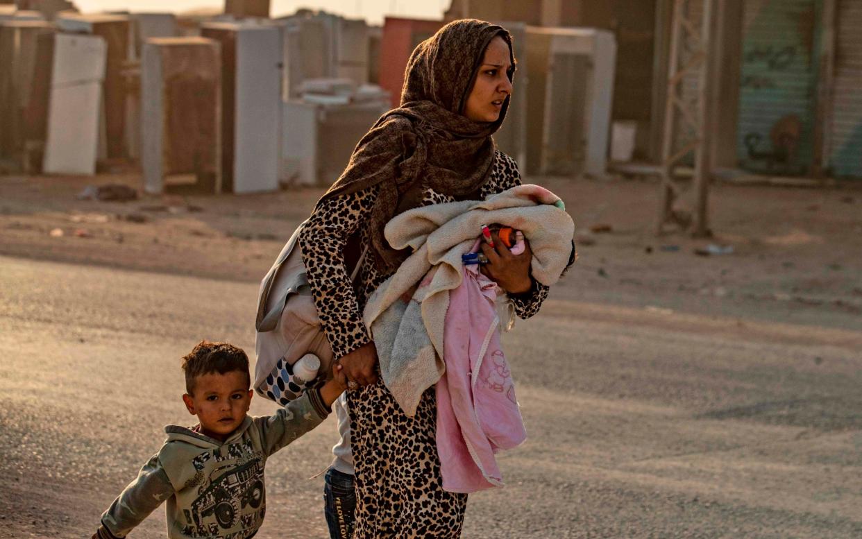 A woman flees with her children in Ras al-Ain as Turkey begins its attack - AFP