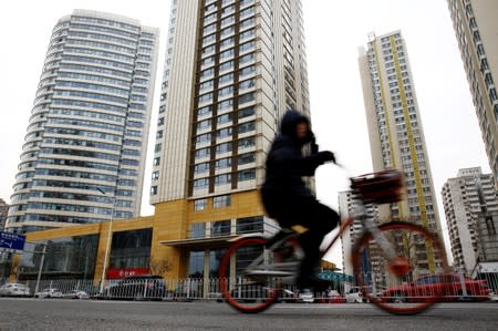 FILE PHOTO: Woman cycles past a building where the Huaying Haitai Science and Technology Development Co is registered, in Tianjin