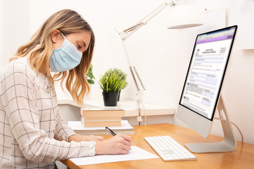 Young business woman working from home wearing protective mask