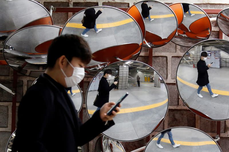 Man wearing a mask to prevent the coronavirus is reflected in the mirrors, in Seoul