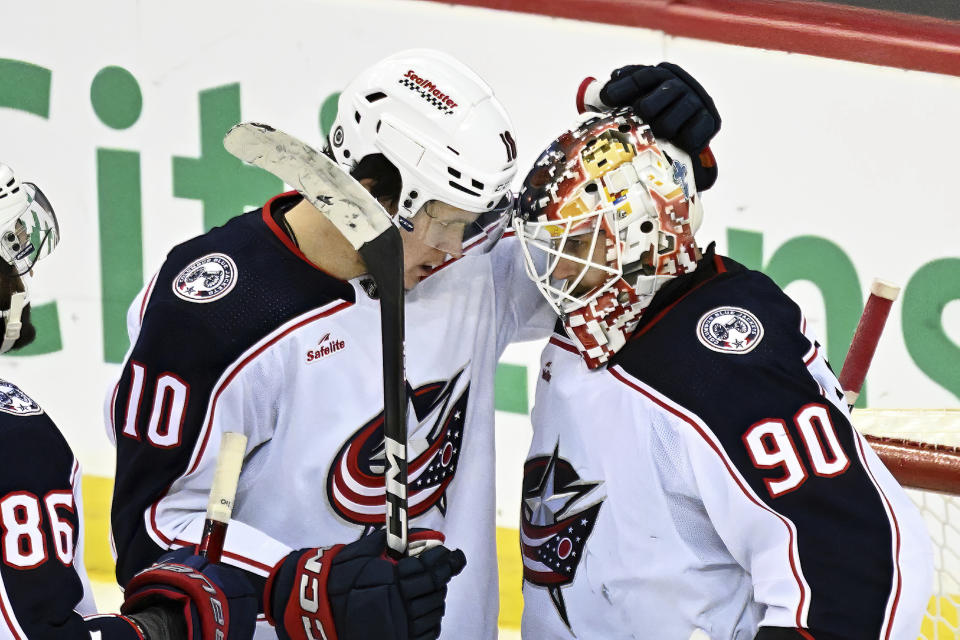 Columbus Blue Jackets left wing Dmitri Voronkov (10) celebrates with goaltender Elvis Merzlikins (90) after the Blue Jackets defeated the New Jersey Devils 2-1 in an NHL hockey game Friday, Nov. 24, 2023, in Newark, N.J. (AP Photo/Bill Kostroun)