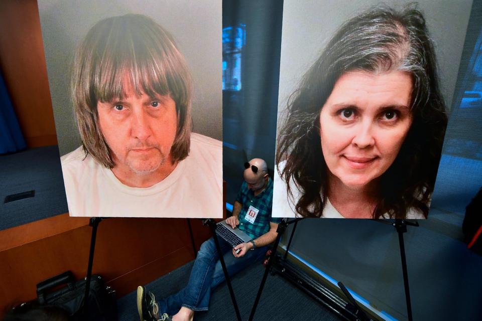 A journalist sits between portraits of David and Louise Turpin (AFP/Getty Images)