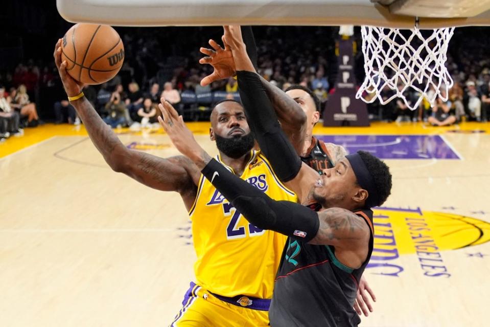 Lakers forward LeBron James shoots as Washington Wizards forward Kyle Kuzma, center, and forward Richaun Holmes defend during the second half. AP