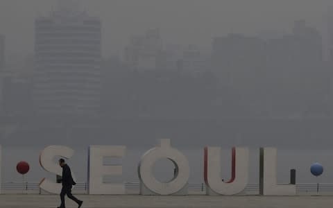 A man wearing a mask walks along the Han river at a park in Seoul, South Korea - Credit: Lee Jin-man/AP