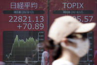 A woman walks past an electronic stock board showing Japan's Nikkei 225 index at a securities firm in Tokyo Wednesday, Aug. 12, 2020. Shares were mostly lower in Asia on Wednesday after Wall Street pumped the brakes on its recent rally. (AP Photo/Eugene Hoshiko)