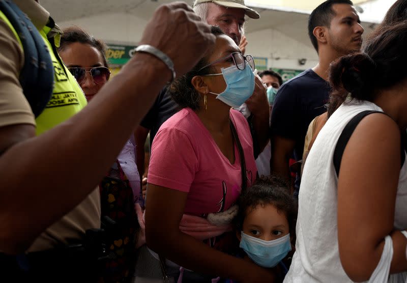 A woman and a child stand in line as they try to buy surgical masks and disinfectant gel at the local pharmacy after the first case of the fast-spreading new coronavirus was confirmed in the country in Guayaquil, Ecuador