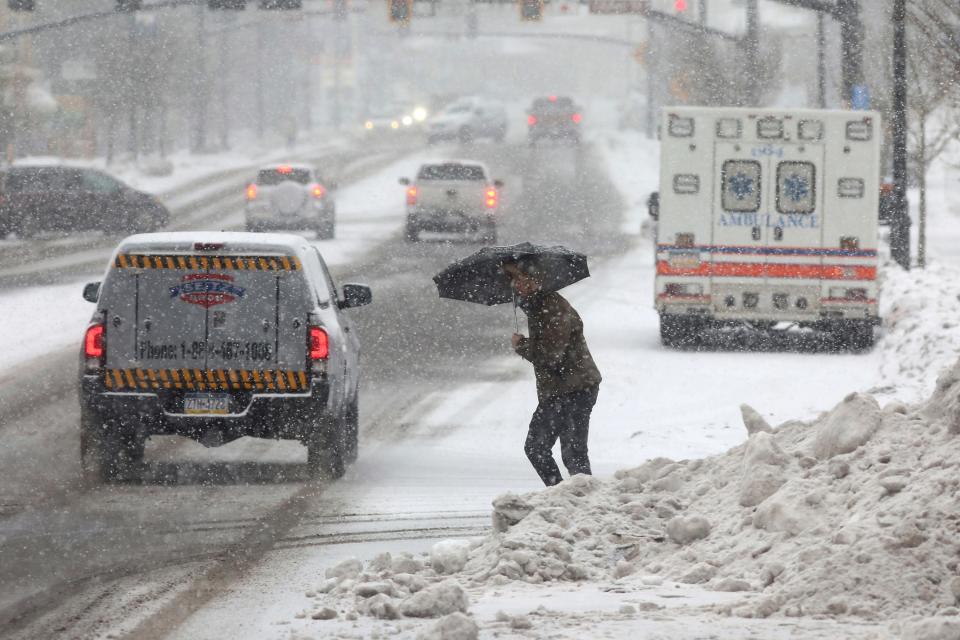 Snow falls in Hazleton, Pennsylvania as someone uses an umbrella to shield themselves on Dec. 22, 2022.