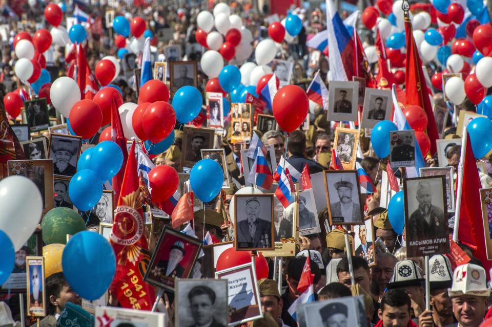 People carry portraits of relatives who fought in World War II, and Russian and Soviet flags, during the Immortal Regiment march through the main street toward Red Square in Moscow, Russia, Thursday, May 9, 2019, celebrating 74 years since the end of WWII and the defeat of Nazi Germany. (AP Photo/Dmitry Serebryakov)