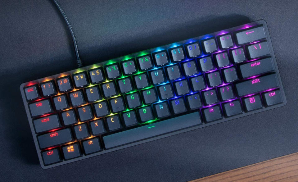 The Razer Huntsman Mini keyboard with rainbow backlights sitting on a black desk pad.