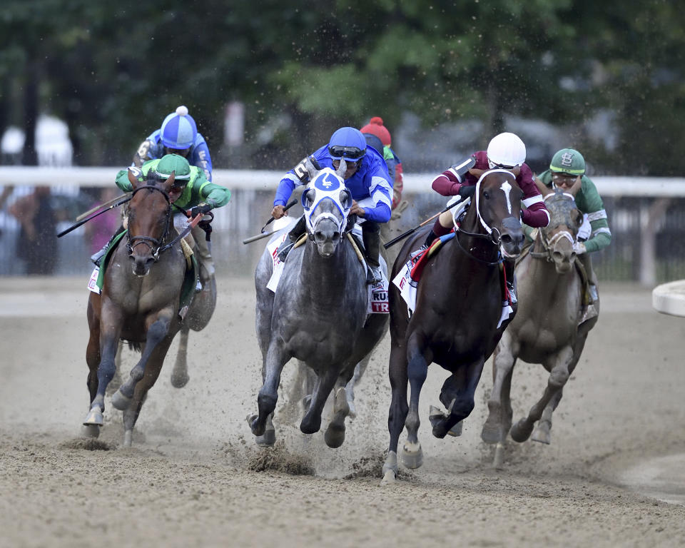 In a photo provided by the New York Racing Association, Essential Quality (2 in blue), with jockey Luis Saez, rounds a turn next to Midnight Bourbon, right front, with Ricardo Santana Jr., during the Travers Stakes horse race Saturday, Aug. 28, 2021, at Saratoga Race Course in Saratoga Springs, N.Y. Essential Quality won the race. (Dom Napolitano/New York Racing Association via AP)