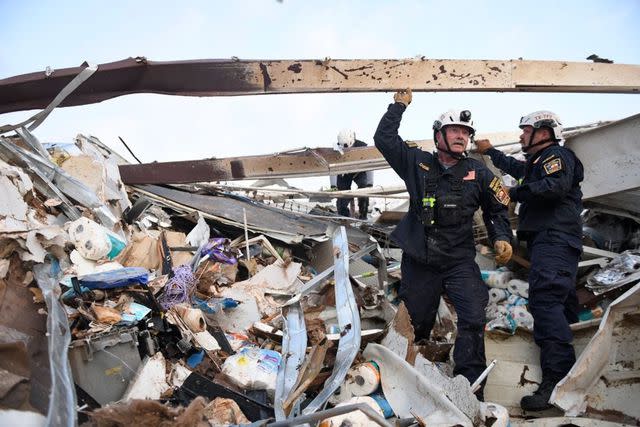 <p>Annie Rice / USA TODAY NETWORK</p> Emergency crew members search through debris the morning after a tornado passed through Matador,