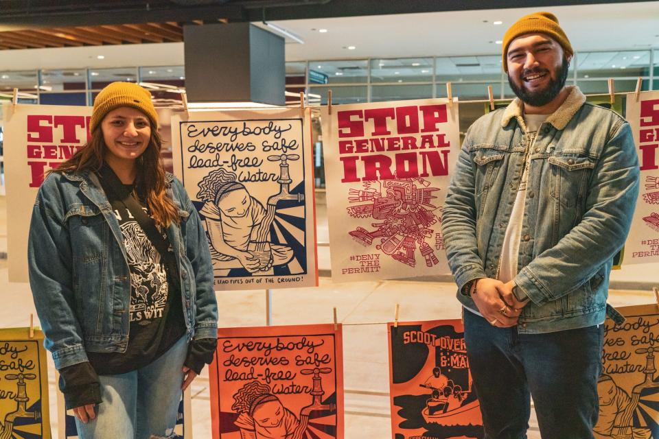 Brenda Santoyo (left), a senior policy analyst with the Little Village Environmental Justice Organization, and Oscar Sanchez (right) stand next to artwork highlighting key community environmental issues at the Justseeds x NRDC Chicago Expo in 2022. Artwork by Monica Trinidad and Grae Rosa.
