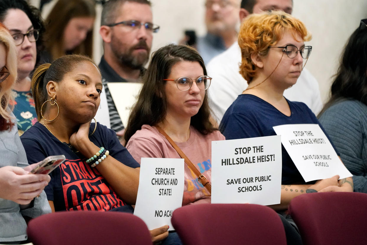 Women hold signs opposing charter schools linked to Hillsdale College during a meeting of the Tennessee Public Charter School Commission staff in Murfreesboro, Tenn., on Sept. 14, 2022. (Mark Humphrey / AP file)