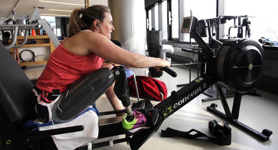 In this Tuesday, March 11, 2014 photo, Boston Marathon bombing survivor Roseann Sdoia works out on a rowing machine at the Spaulding Rehabilitation Hospital in Boston. Sdoia goes to Spaulding twice a week for hour-long workouts with a physical therapist, and then she usually hops on the rowing machine to build her endurance after her therapy session. She aims to run again, a hobby she loved doing before her injury. (AP Photo/Charles Krupa)