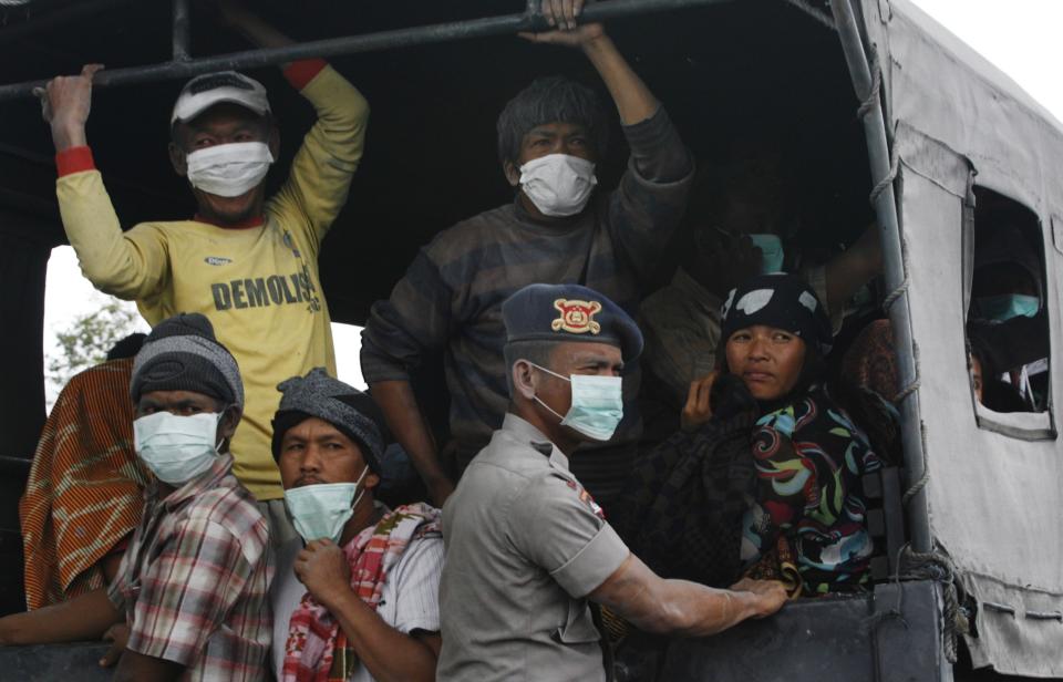 Villagers covered in ash sit on a truck while waiting to be evacuated to safety, as Mount Sinabung spews ash and hot lava during an eruption in Perteguhan village