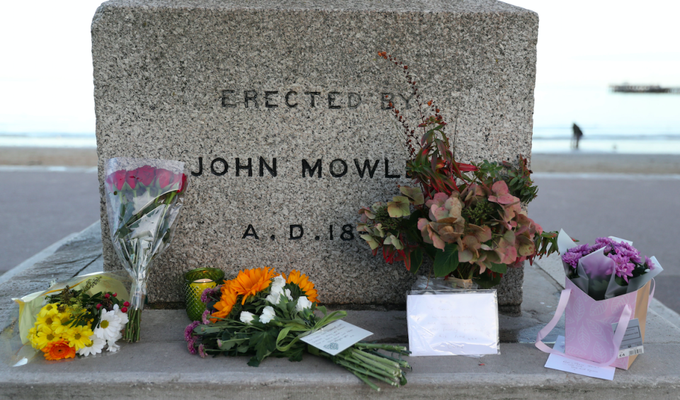 <em>Floral tributes have begun to be left on the Alfred Monument, next to the sea front (PA)</em>