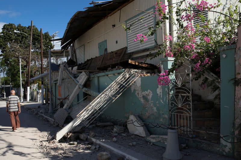 A man walks past a damaged house after an earthquake in Guanica