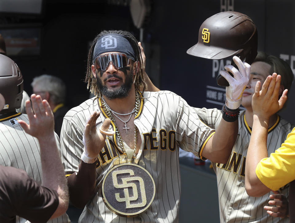 San Diego Padres' Fernando Tatis Jr. gets high fives in the dugout after hitting a two run home run during the fifth inning in the first game of a baseball doubleheader against ther Atlanta Braves Wednesday, July 21, 2021, in Atlanta. The Padres won 3-2. (Curtis Compton/Atlanta Journal-Constitution via AP)