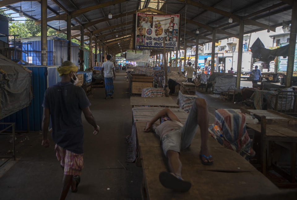 Workers rest at a wholesale market closed to curb the spread of the coronavirus in Colombo, Sri Lanka on June 16, 2021. Sri Lanka has cut back on imports of farm chemicals, cars and even its staple spice turmeric as its foreign exchange reserves dwindle, hindering its ability to repay a mountain of debt as the South Asian island nation struggles to recover from the pandemic. (AP Photo/Eranga Jayawardena)