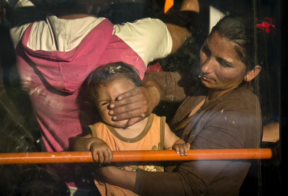 A Romanian Roma woman expelled from France wipes a baby's face after boarding a crowded bus at Bucharest's Henri Coanda international airport in Otopeni, Romania, Thursday, Sept. 13, 2012. French Interior Minister Manual Valls,on a two-day official visit to Romania, discuss with Romanian authorities the issue of Roma immigration to France and ways to support Roma inclusion. (AP Photo/Vadim Ghirda)