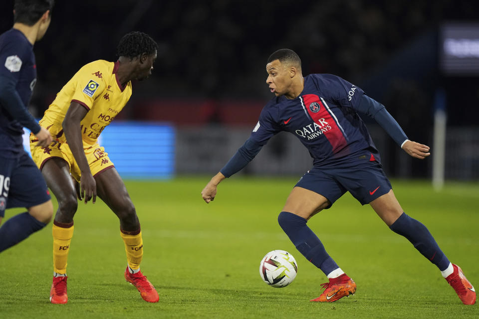 PSG's Kylian Mbappe, right, challenges for the ball with Metz's Joseph N'Duquidi, during the French League One soccer match between Paris Saint-Germain and Metz at the Parc des Princes in Paris, Wednesday, Dec 20, 2023. (AP Photo/Michel Euler)