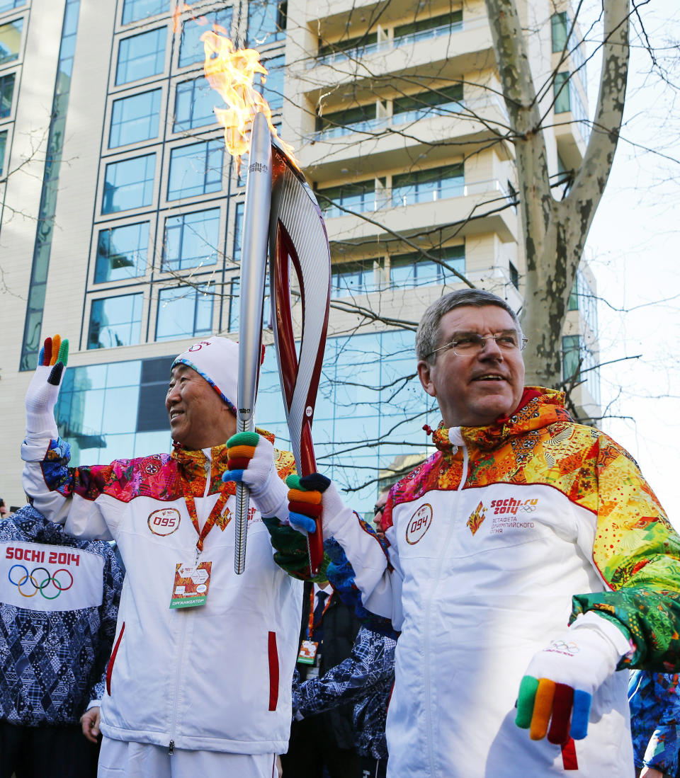 IOC President Thomas Bach, right, hands over the Olympic torch to United Nations Secretary-General Ban Ki-moon as the torch relay arrives in Sochi, ahead of the 2014 Winter Olympics, Thursday, Feb. 6, 2014, in Russia. (AP Photo/Shamil Zhumatov, Pool)