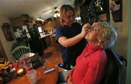 Sandy Wright (R) has eyedrops applied by her C.N.A. (Certified Nursing Assistant) Jessica Haynes at her home in Peoria, Illinois, November 25, 2013. REUTERS/Jim Young