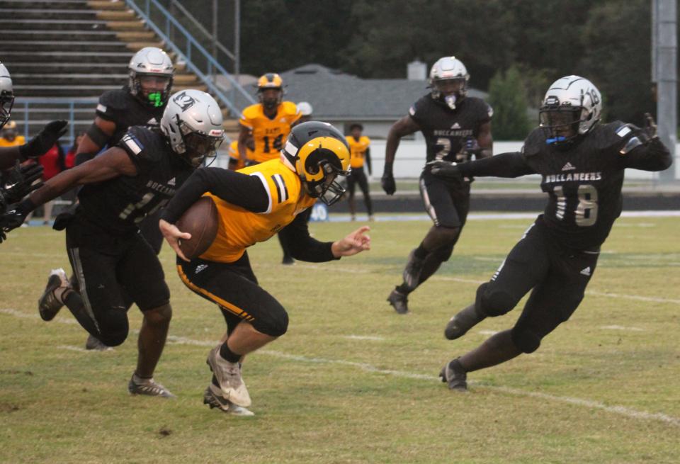 Englewood quarterback Sean Wilks (1) tries to escape the pass rush of First Coast's Samuel Olunuga (15) and Geah Kai (18)  during a high school football game on October 3, 2022. [Clayton Freeman/Florida Times-Union]