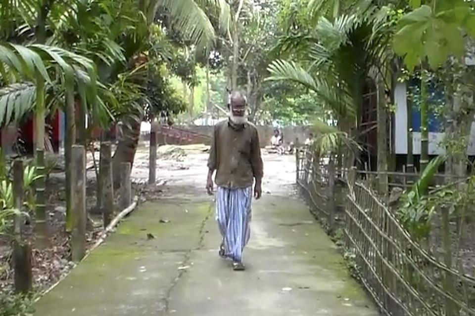 Mr Ali walks through his village of Sunamganu (AP)