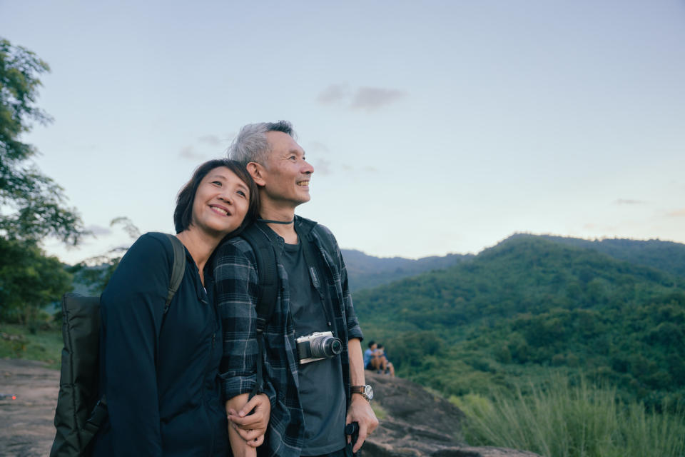 A middle-aged couple smile as they look out on the horizon after hiking 