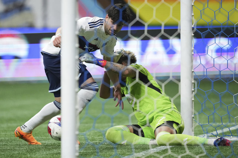 Vancouver Whitecaps' Brian White, left, scores his second goal against Minnesota United goalkeeper Dayne St. Clair during the second half of an MLS soccer match in Vancouver, British Columbia., Saturday, May 6, 2023. (Darryl Dyck/The Canadian Press via AP)