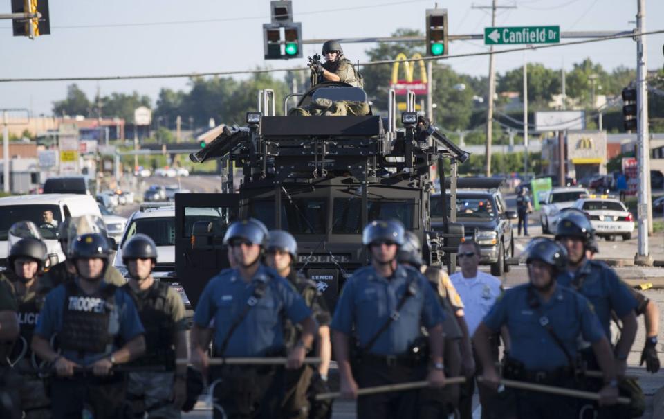 <p>Riot police stand guard as demonstrators protest the shooting death of teenager Michael Brown in Ferguson, Missouri August 13, 2014. Police in Ferguson fired several rounds of tear gas to disperse protesters late on Wednesday, on the fourth night of demonstrations over the fatal shooting of an unarmed black teenager Brown, 18, by a police officer on August 9 after what police said was a struggle with a gun in a police car. A witness in the case told local media that Brown had raised his arms to police to show that he was unarmed before being killed. (Mario Anzuoni/Reuters) </p>