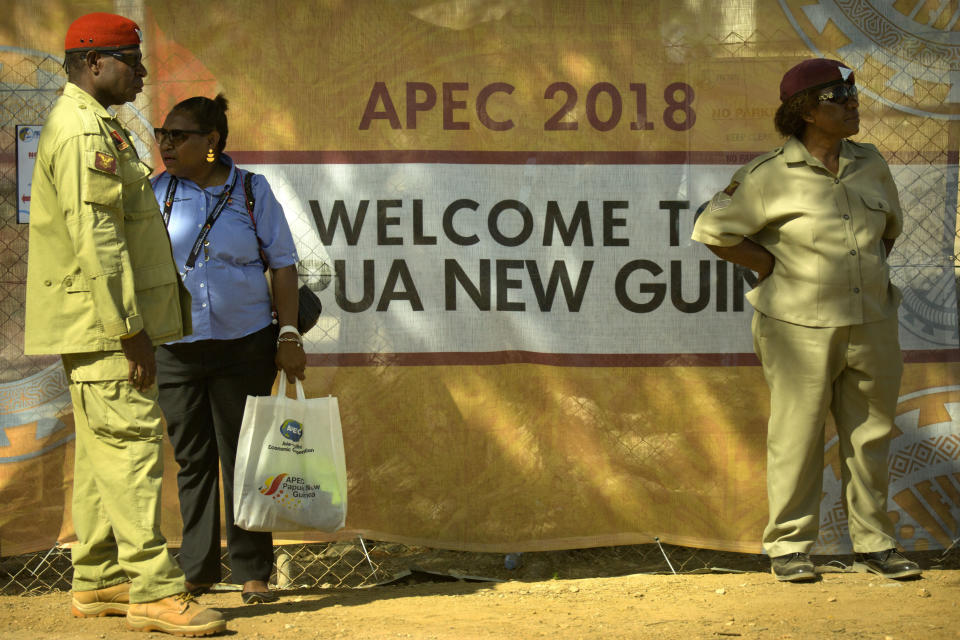 Security officials stand outside a perimeter fence for a secured area ahead of the APEC Economic Leaders' Week Summit in Port Moresby, Papua New Guinea, Wednesday, Nov. 14, 2018. After three decades of promoting free trade as a panacea to poverty, the APEC grouping of nations that includes the U.S. and China is holding its lavish annual leaders meeting in the country that can least afford it. (AP Photo/Mark Schiefelbein)