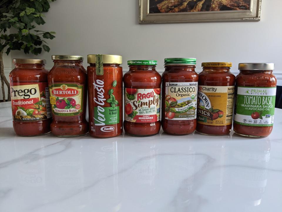 A line of seven red pasta sauces on a white kitchen counter