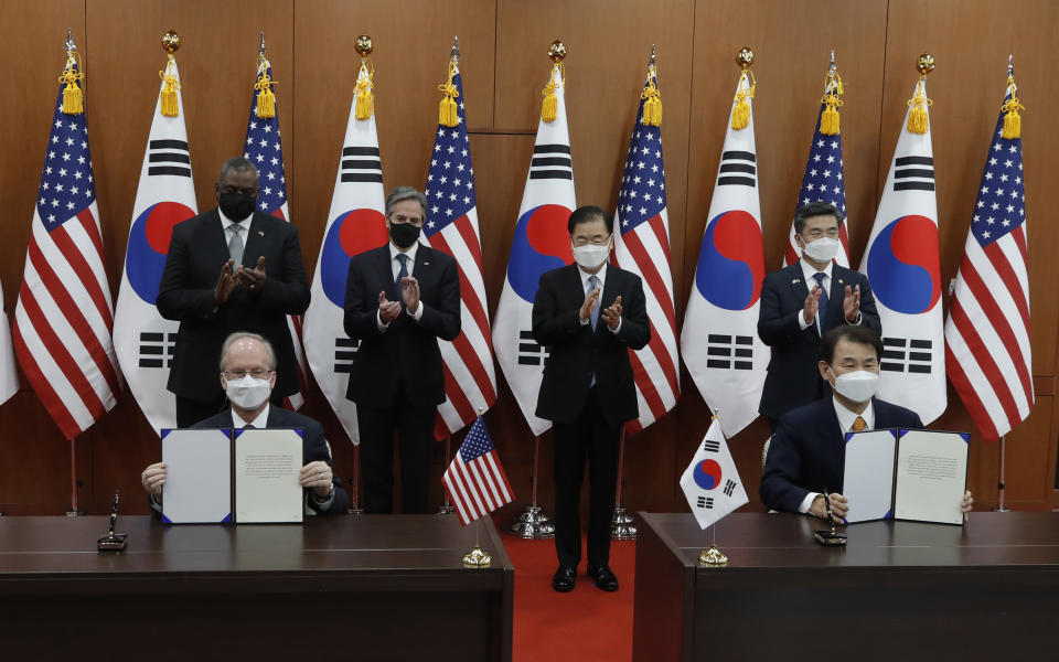 Robert Rapson, Chargé d'Affaires ad interim at U.S. Embassy, left sitting, and South Korea's chief negotiator Jeong Eun-bo, right sit, hold documents as U.S. Secretary of State Antony Blinken, second from left, U.S. Defense Secretary Lloyd Austin, left, South Korean Foreign Minister Chung Eui-yong, second from right, and South Korean Defense Minister Suh Wook, right, clap during an initialing ceremony for Special Measures Agreement at the Foreign Ministry in Seoul, South Korea, Thursday, March 18, 2021. (AP Photo/Lee Jin-man, Pool)