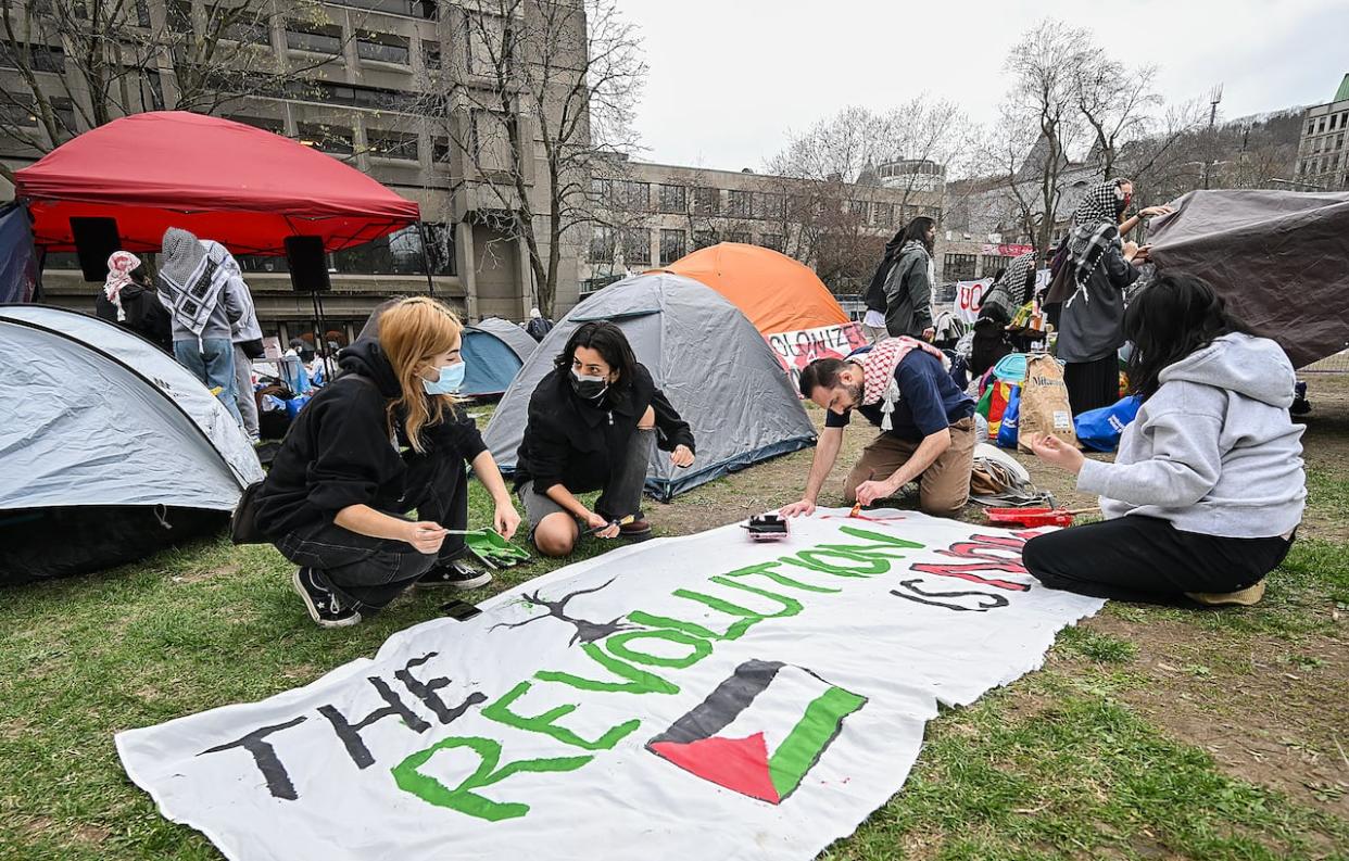 People work on a sign during a pro-Palestinian demonstration at an encampment at McGill University in Montreal, Saturday, April 27, 2024. (Graham Hughes/The Canadian Press - image credit)