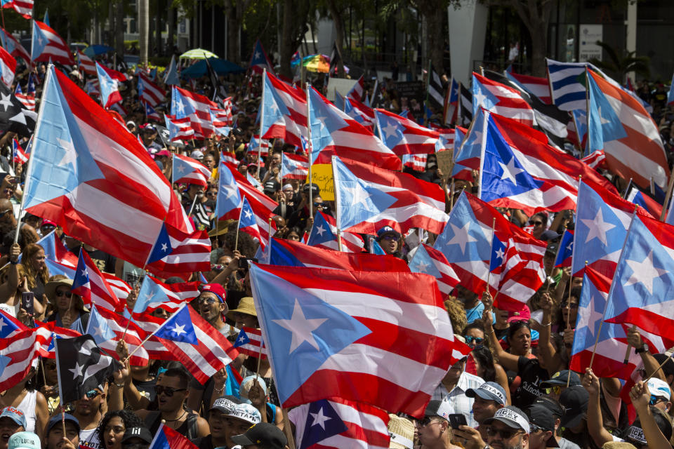 People march with Puerto Rican national flags to celebrate the resignation of Gov. Ricardo Rossello who announced overnight that he is resigning Aug. 2 after weeks of protests over leaked obscene, misogynistic online chats, in San Juan, Puerto Rico, Thursday, July 25, 2019. (AP Photo/Dennis M. Rivera Pichardo)