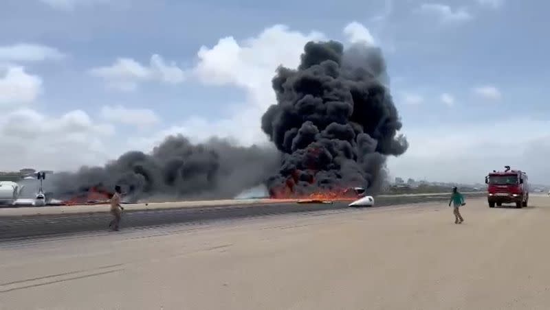 Smoke billows from a plane that flipped over after a crash landing, in Mogadishu