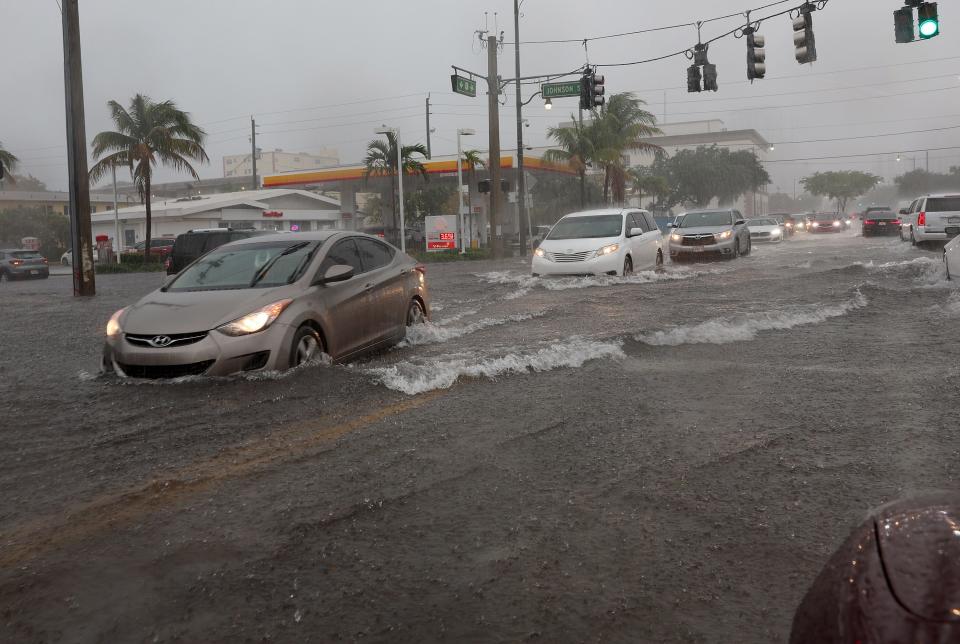 Cars drive through a flooded street on April 12, 2023 in Dania Beach, Florida.