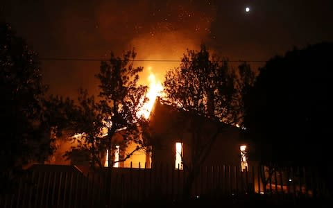 A house burns in the town of Mati, east of Athens - Credit: AP