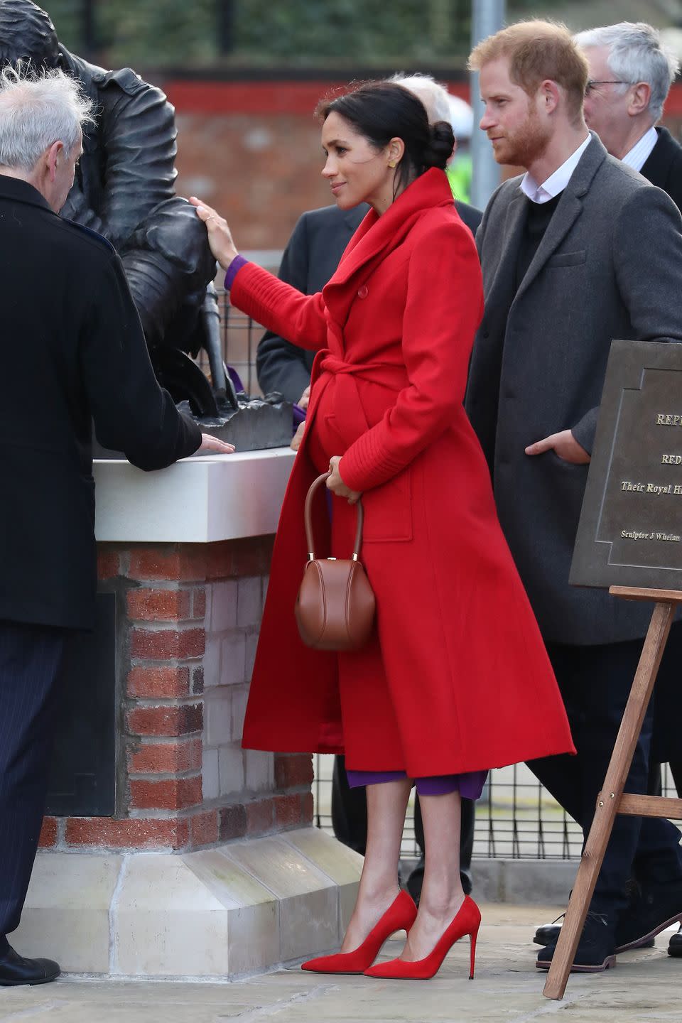 <p>The Duchess chose a bold coat with red heels for her first joint engagement with Prince Harry of the year. She paired the bright red look with matching heels and a purple dress for her day of events in Birkenhead.</p>