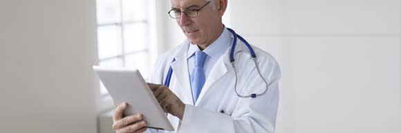 A doctor works on a tablet computer.